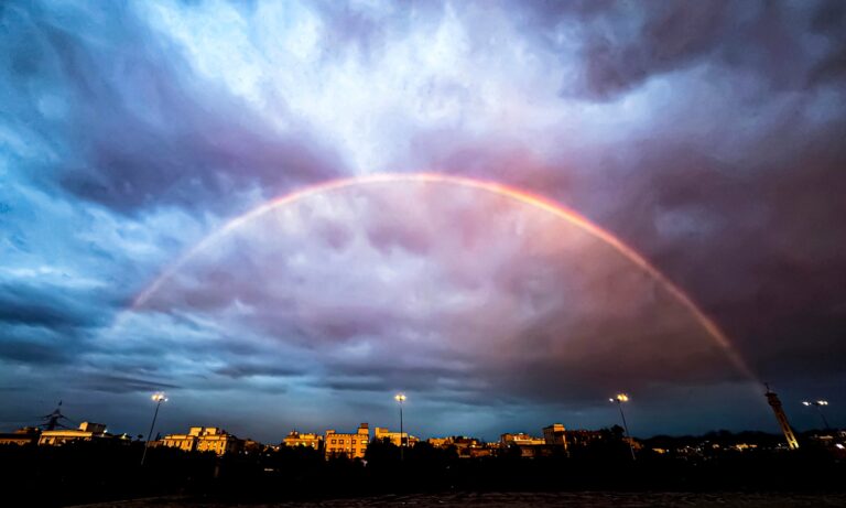 Fotografía de un arcoíris completo en el cielo después de una lluvia.