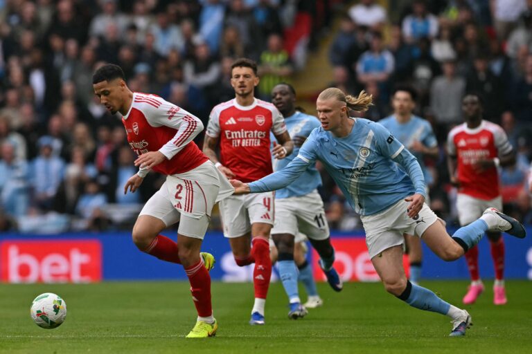 Los escudos del Arsenal y el Manchester City enfrentados, representando el partido clave de la Premier League.