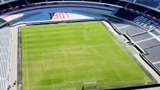 Vista aérea del campo de juego del estadio Monumental, donde se observan sectores con césped ralo y zonas con arena.