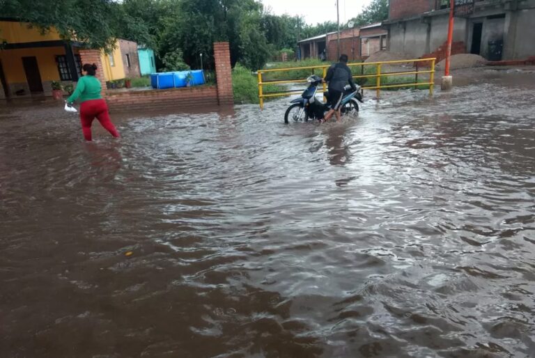Calle anegada en Tucumán durante el temporal, con personal de emergencias trabajando en el lugar.