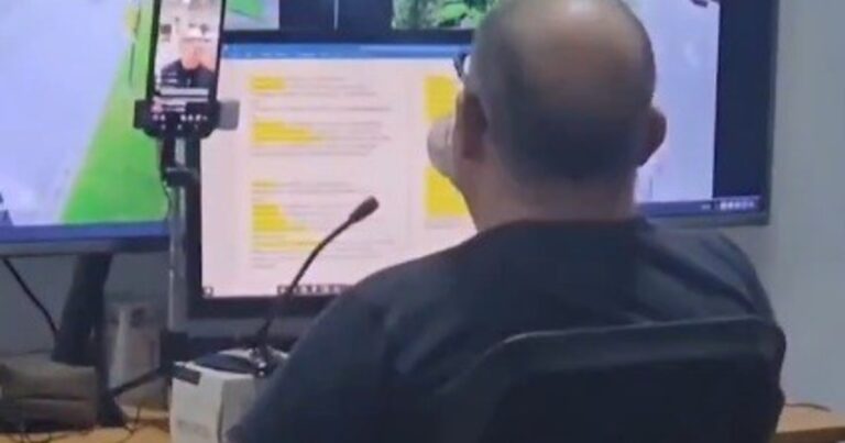 Operario sentado frente a monitores de seguridad en centro de monitoreo