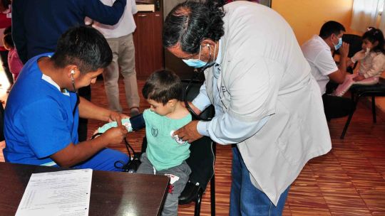 Niño en consultorio médico con su madre, simbolizando el acceso a la salud infantil en Argentina