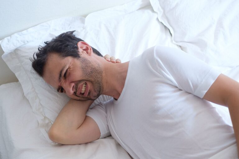 Almohada ergonómica sobre una cama con sábanas de algodón