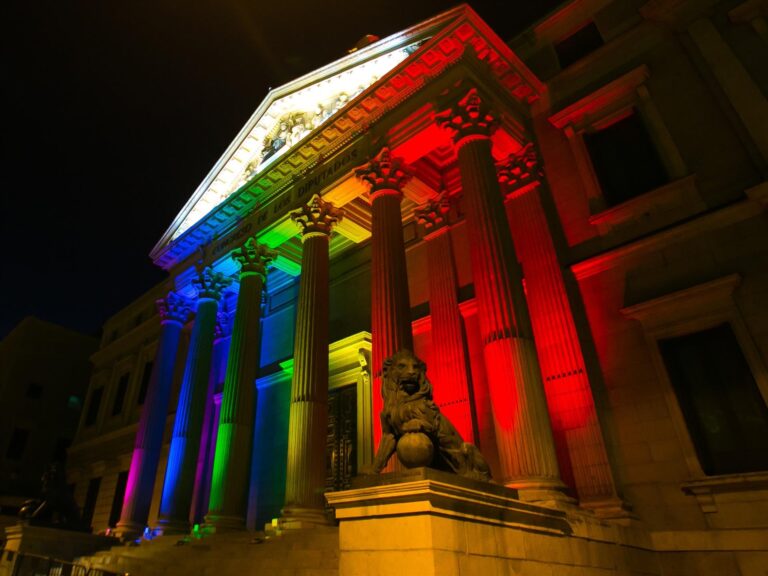 Fachada del Congreso de los Diputados iluminada con los colores de la bandera LGTBI+