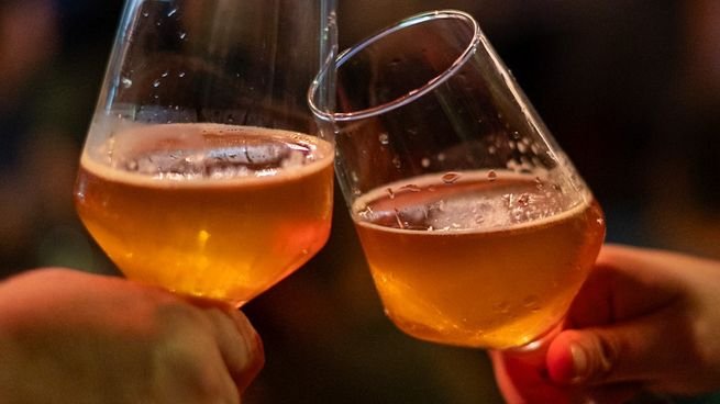 Personas brindando con vasos de cerveza artesanal en un bar de Buenos Aires
