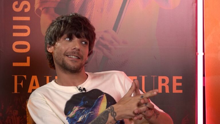 Louis Tomlinson sonriente con una chaqueta de Boca Juniors durante una entrevista virtual