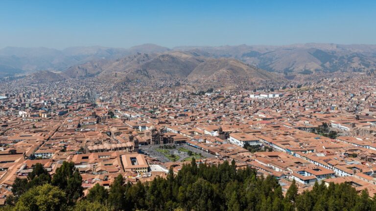 Vista de la ciudad de Cusco con cielo nublado y montañas de fondo