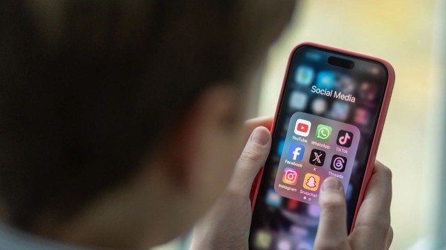 Persona mirando su teléfono con íconos de redes sociales y un candado digital representando la protección de la identidad