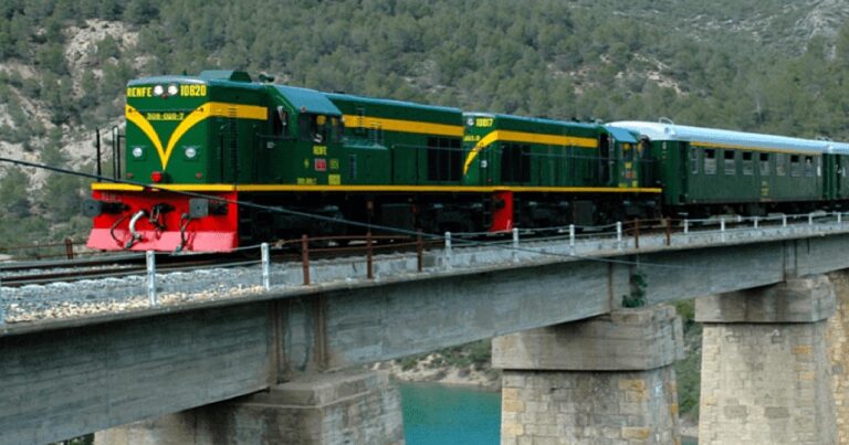 Tren histórico recorriendo el paisaje montañoso del Prepirineo catalán junto a un lago