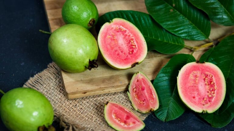 Zumo de guayaba en un vaso junto a guayabas enteras