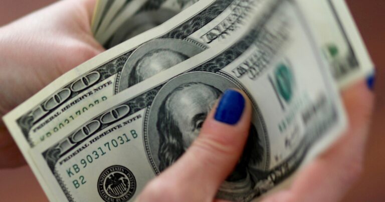 Billetes de dólar y monedas de sol peruano sobre una superficie plana