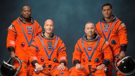 Astronautas de la misión Artemis III posando con trajes espaciales ante un fondo de la Luna