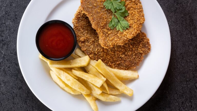 Cachopo de pollo empanado y dorado sobre una tabla de madera
