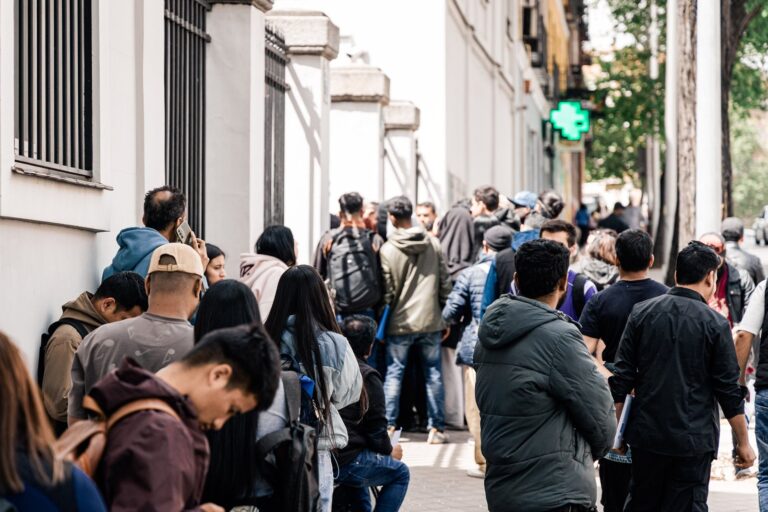 Personas migrantes en fila para trámites de regularización en España