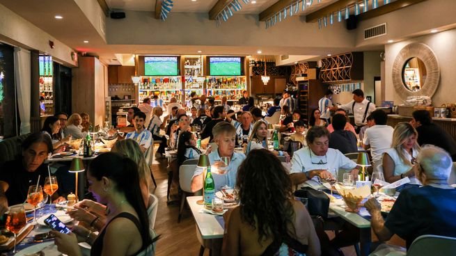 Interior de un local de Baires Grill con decoración celeste y blanca y pantalla gigante para la final del Mundial 2026