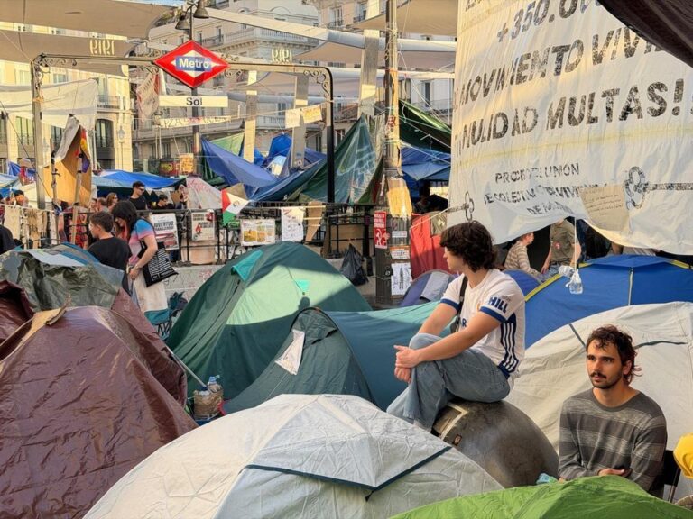 Carpas del acampe por la vivienda en la Puerta del Sol de Madrid, con turistas y comercios alrededor