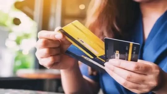 Persona revisando documentos financieros y tarjetas de crédito en un escritorio